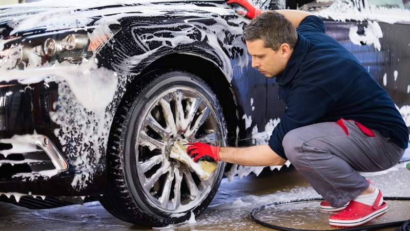 Man washing car tires at a car wash